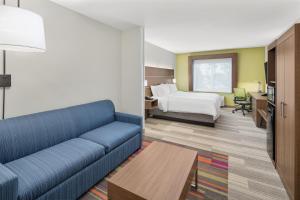 un salon avec un canapé et un lit ainsi qu'une chambre dans l'établissement Holiday Inn Express Hotel & Suites Palm Bay, an IHG Hotel, à Palm Bay