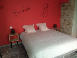 een slaapkamer met een wit bed en een rode muur bij Gite de la Bultiere 4 etoiles ouvert a l'annee entre Montaigu et les Herbiers in Chavagnes-en-Paillers