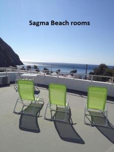 佩里薩的住宿－Sagma Beach Rooms，海滩旁的天井上摆放着三把绿色椅子