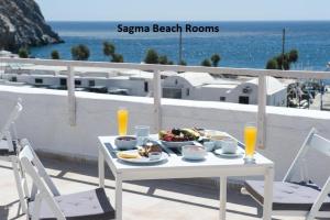 a table with a bowl of food on a balcony with the ocean at Sagma Beach Rooms in Perissa