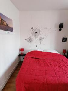 a bedroom with a red bed and dandelions on the wall at Maison MooMoons in Vaubadon