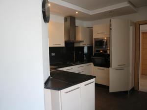a kitchen with white cabinets and a black counter top at Appartment Central Hammam Sousse plage in Sousse