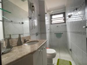 La salle de bains est pourvue d'un lavabo, de toilettes et d'un miroir. dans l'établissement Apartamento Maravilhoso, à Capão da Canoa