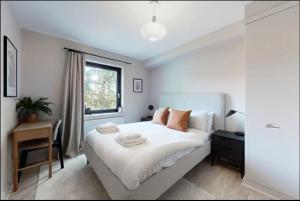 a bedroom with a bed and a desk and a window at Modern 2 bedroom flat with patio in Turnpike Lane in London