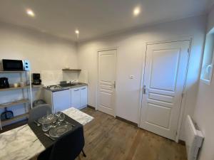 eine kleine Küche mit einem Tisch und einer weißen Tür in der Unterkunft Studio 41 in Eppeville