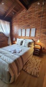 Cama grande en habitación con pared de ladrillo en Duplex estilo europeu Ednamar Apartamentos Bérgamo, en Gramado