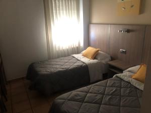 a bedroom with two beds and a window at Hostal De La Rosa in Valdemoro