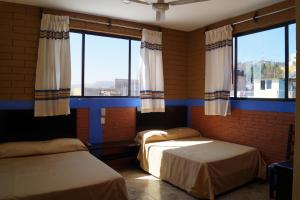2 camas en una habitación con 2 ventanas en Casa Xochimilco, en Oaxaca City