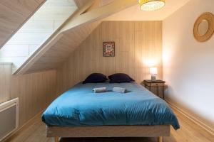 a bedroom with a blue bed in a attic at Le 32-GregIMMO-Appart'Hôtel in Montbéliard