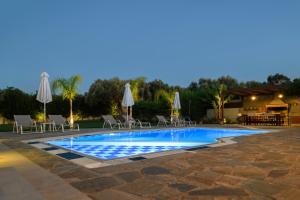 a large swimming pool with chairs and umbrellas at Villa Periklis in Adelianos Kampos