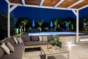 patio con sofá y piscina por la noche en Villa Periklis, en Adelianos Kampos