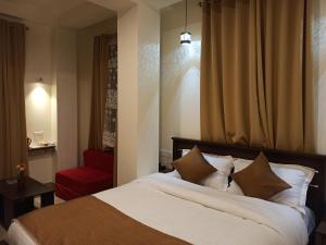a bedroom with a large bed and a red chair at Vanagleda-A Boutique Guest House in Shillong