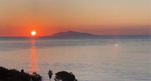 a sunset over the ocean with a mountain in the background at Chjama di mare in Santa-Maria-di-Lota