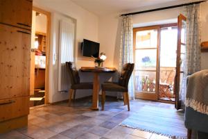ein Wohnzimmer mit einem Tisch und Stühlen sowie einem Balkon in der Unterkunft Ferienwohnung Goller in Lenggries