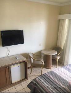 a hotel room with a bed and a table and a tv at Flat no Costa Mar Recife in Recife