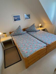 1 Schlafzimmer mit einem Holzbett mit blauer Bettwäsche und 2 Tischen in der Unterkunft Haus Windjammer in Friedrichskoog
