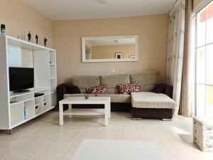 Una sala de estar con un sofá y un televisor. en La Palma, en Costa Calma