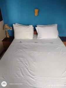 uma cama grande com lençóis brancos e uma parede azul em Pousada Mar de Araçatiba em Praia de Araçatiba