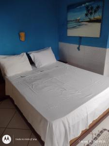 a large bed in a room with a blue wall at Pousada Mar de Araçatiba in Praia de Araçatiba