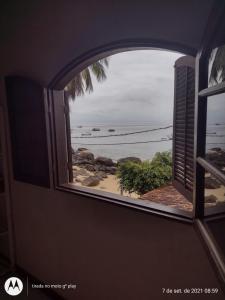 uma janela aberta com vista para a praia em Pousada Mar de Araçatiba em Praia de Araçatiba
