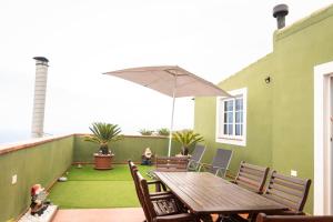 patio z drewnianym stołem, krzesłami i parasolem w obiekcie Green Sky w mieście San Juan de la Rambla