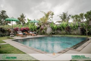 烏布的住宿－Green Padma Ubud，一个带两把椅子和遮阳伞的游泳池