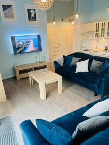 a living room with a blue couch and a table at Apartament Marina in Dziwnówek