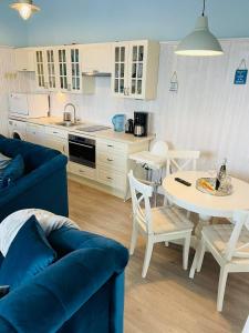 eine Küche und ein Wohnzimmer mit einem blauen Sofa und einem Tisch in der Unterkunft Apartament Marina in Dziwnówek