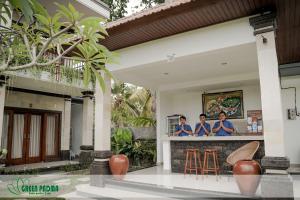 uma casa com TV na parede com três mulheres em Green Padma Ubud em Ubud