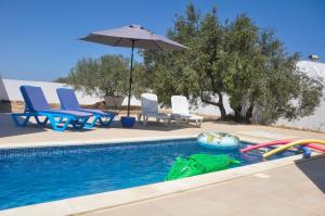 einen Pool mit einem Poolspielzeug und einem Sonnenschirm in der Unterkunft Villa Salem Maison d'architecte toute équipée & piscine in Arkou