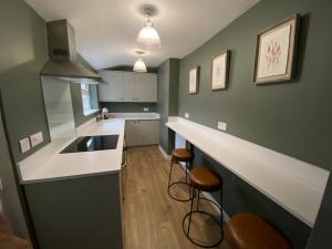 a kitchen with green walls and a counter and stools at Durham Road - Zillo in Spennymoor