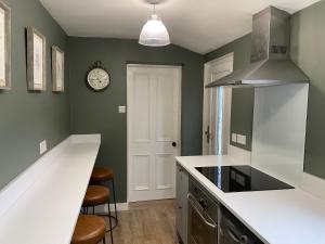 a kitchen with green walls and a clock on the wall at Durham Road - Zillo in Spennymoor