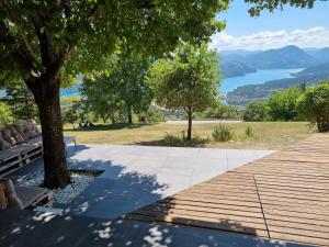a wooden walkway with a bench and a view of a lake at Belle maison Vue imprenable lac de Serre-Ponçon in Prunières +25 photos