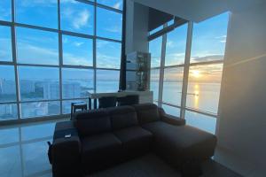 a living room with a couch in front of a large window at The Maritime Suite @ Panoramic Duplex 海景の家 in Jelutong