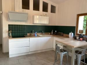 une cuisine avec des placards blancs et une table en bois dans l'établissement Maison de Campagne by La Boîte En Plus, à Senlis