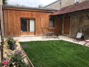 a backyard with a lawn and a table and chairs at Maison de Campagne by La Boîte En Plus in Senlis