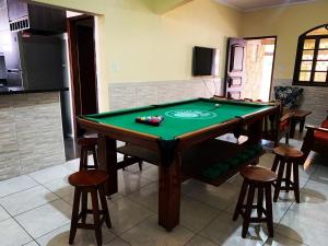 una mesa de billar en una sala de estar con taburetes en Linda casa de Veraneio en Guarujá
