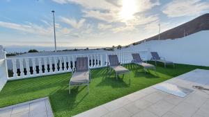 grupa krzeseł siedzących na trawie na balkonie w obiekcie Stunning sea view villa with 6 bedrooms & heated pool - Villa Renaissance w mieście Playa Blanca