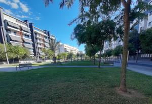 a park with benches and trees in front of buildings at Piso céntrico con piscina,parking y jacuzzi in Córdoba