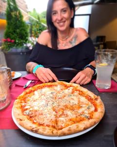 une femme assise à une table avec une pizza dans l'établissement Schönblick Residence - Absolut Alpine Apartments, à Zell am See