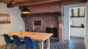 ein Esszimmer mit einem Tisch und einem gemauerten Kamin in der Unterkunft Hoeve Spyckergoed in De Haan