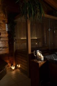 Mini spa in chalet bosco في تْشيستيرنِنو: غرفة مع ساونا مع الشموع وكؤوس النبيذ