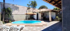 einen Pool auf einer Terrasse mit Stühlen und einem Sonnenschirm in der Unterkunft Linda casa c/ piscina e conforto próximo do Mar in Itapoa