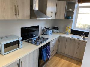 a kitchen with a stove top oven next to a microwave at Honeybee Cottage, with a log fire & a hot tub. in Bradford