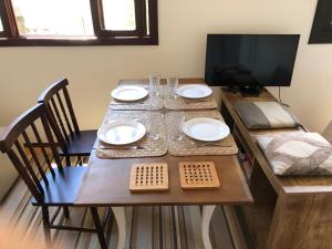 a wooden table with plates and glasses and a television at POA Auxiliadora melhor opção in Porto Alegre