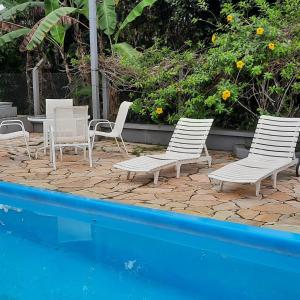 um grupo de cadeiras e uma mesa ao lado de uma piscina em Santa Hospedaria Beach em Bertioga