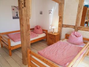 a room with three bunk beds with pink sheets at Große Bauernhaus Ferienwohnungen bis 100qm mit Grillhütte & Garten & E-Bike-Verleih in Bad Rothenfelde