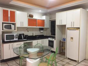 une cuisine avec une table en verre et des placards blancs dans l'établissement APARTAMENTO 3 DORM., O QUINTAL É A PRAIA E MOLHES, à Laguna