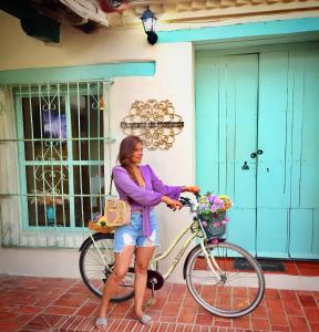 una mujer parada junto a una bicicleta con una cesta en Casa Portales de Santa Bárbara, en Mompox
