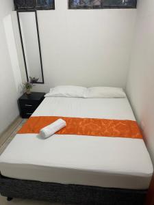 ein Bett mit einer orangefarbenen und weißen Decke drauf in der Unterkunft Cabaña Gaia Rodadero in Santa Marta